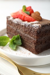 Photo of Piece of delicious chocolate cake with strawberry, almonds and mint on table, closeup