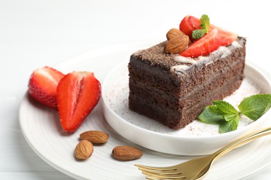 Photo of Piece of delicious chocolate cake with strawberries, almonds and mint on table, closeup