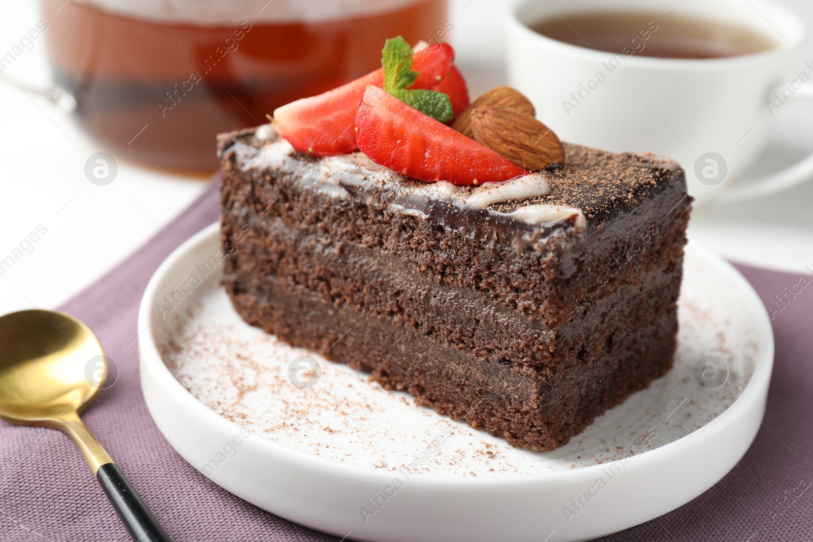 Piece of delicious chocolate cake with strawberry, almonds and tea on table, closeup Photo of Piece of delicious chocolate cake with strawberry, almonds and tea on table, closeup