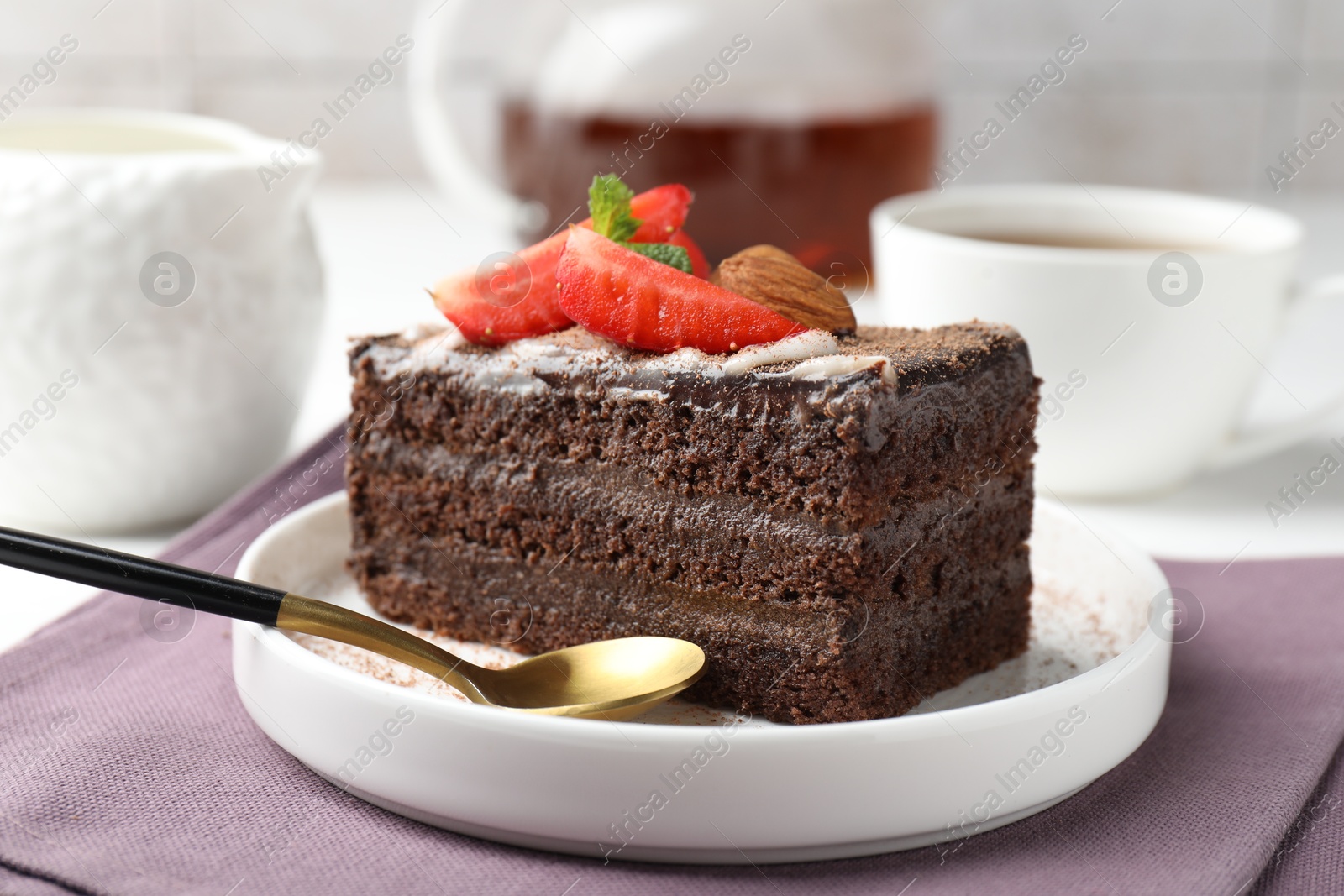 Piece of delicious chocolate cake with strawberry, almonds and tea on table, closeup Photo of Piece of delicious chocolate cake with strawberry, almonds and tea on table, closeup