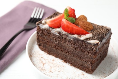 Photo of Piece of delicious chocolate cake with strawberry and almonds on table, closeup