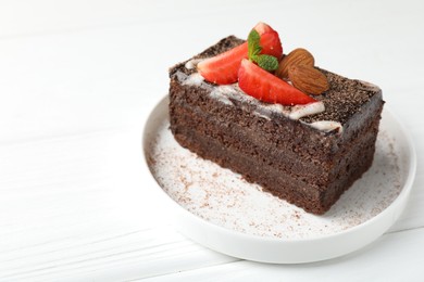 Photo of Piece of delicious chocolate cake with strawberry and almonds on white wooden table, closeup. Space for text