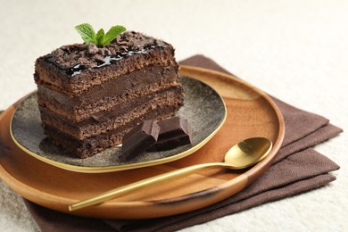 Photo of Piece of delicious chocolate cake with mint on white textured table, closeup