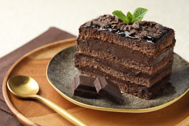 Photo of Piece of delicious chocolate cake with mint on table, closeup