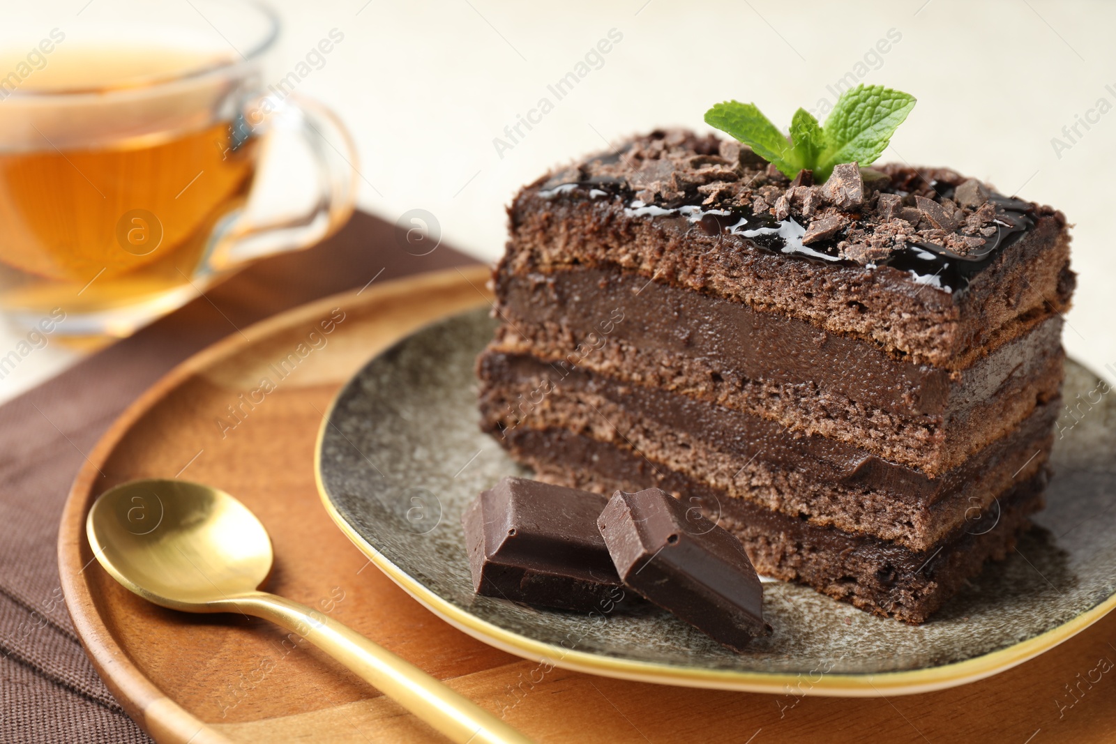 Piece of delicious chocolate cake with mint and tea on table, closeup Photo of Piece of delicious chocolate cake with mint and tea on table, closeup
