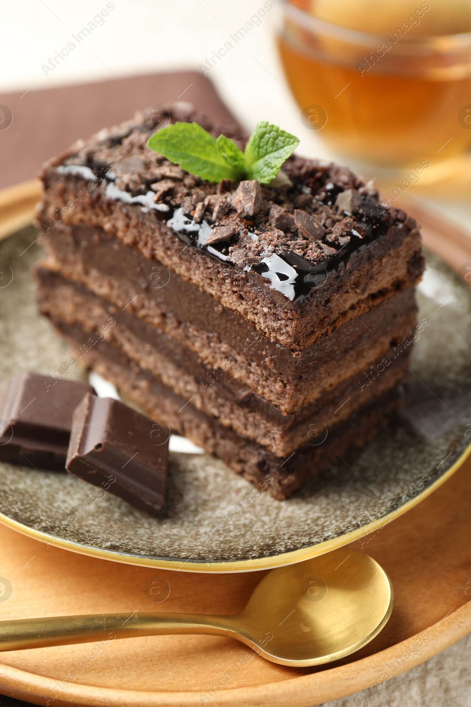 Piece of delicious chocolate cake with mint and tea on table, closeup Photo of Piece of delicious chocolate cake with mint and tea on table, closeup