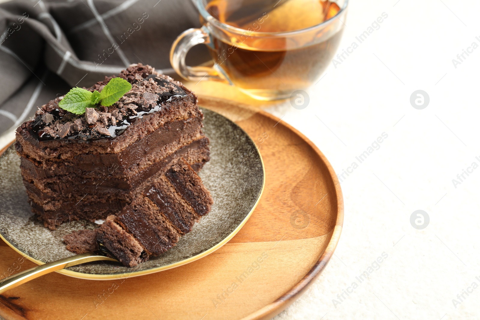Piece of delicious chocolate cake with mint and tea on white table, closeup. Space for text Photo of Piece of delicious chocolate cake with mint and tea on white table, closeup. Space for text