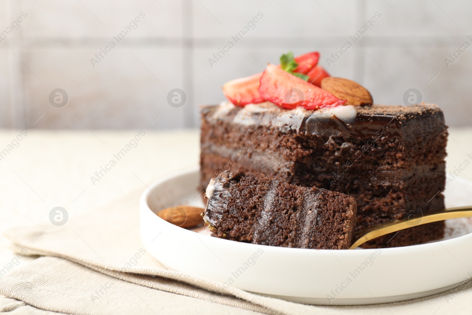 Photo of Piece of delicious chocolate cake with strawberry and almonds on table, closeup. Space for text