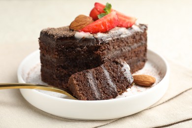 Photo of Piece of delicious chocolate cake with strawberry and almonds on table, closeup
