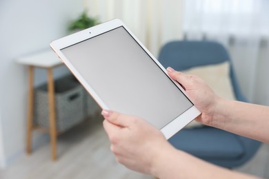 Photo of Woman with modern tablet at home, closeup