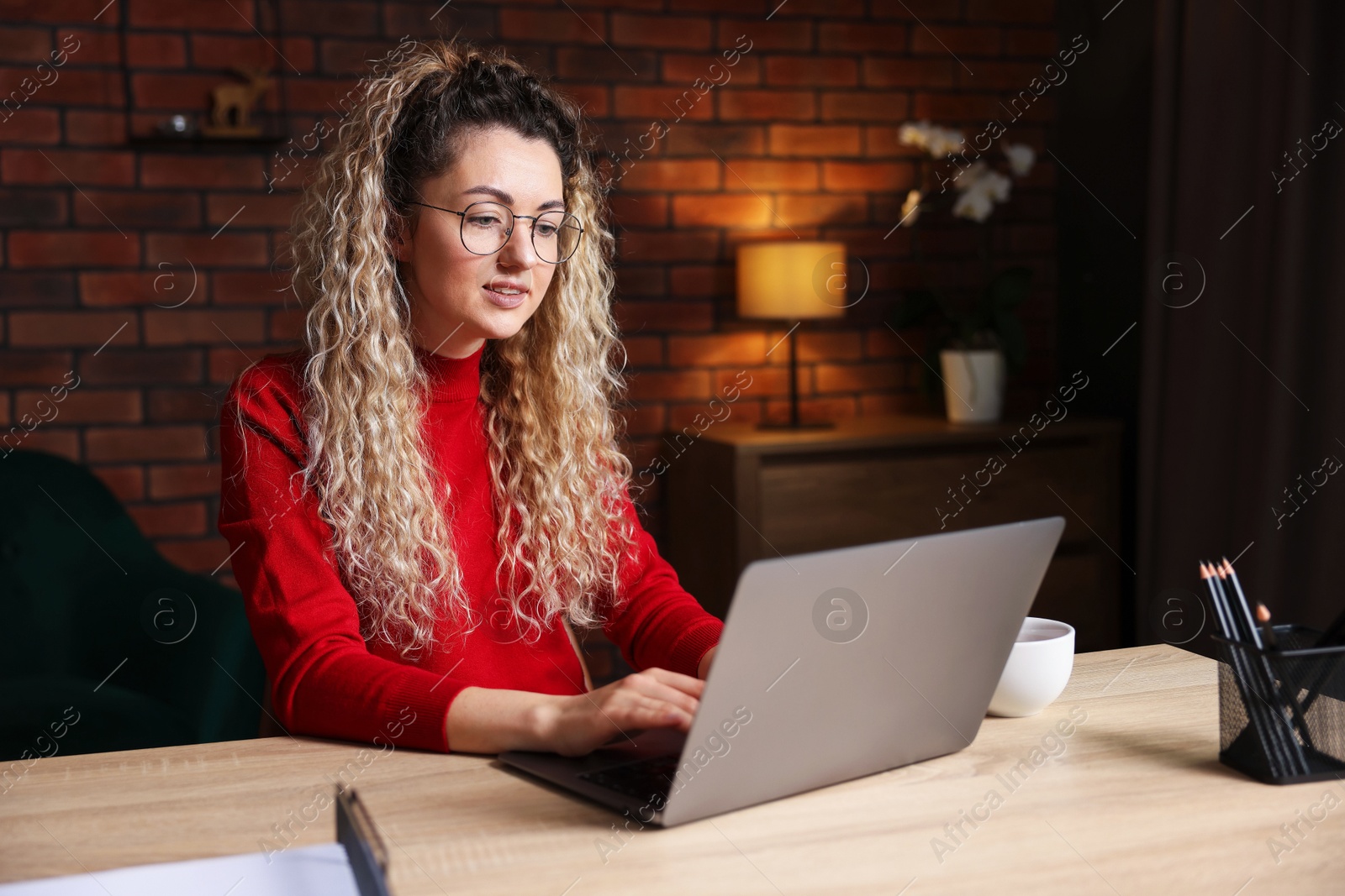 Woman working with laptop at desk in home office Photo of Woman working with laptop at desk in home office