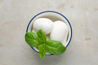 Photo of Tasty mozzarella cheese and basil on light table, top view