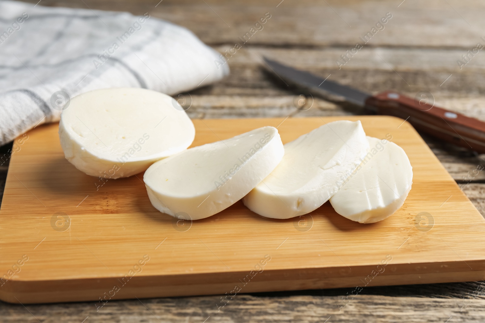 Cut mozzarella cheese and knife on wooden table, closeup Photo of Cut mozzarella cheese and knife on wooden table, closeup