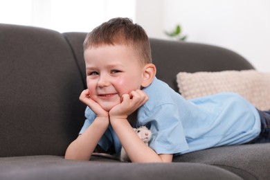 Photo of Little boy with his pet rat on sofa at home