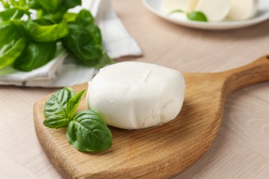 Photo of Piece of delicious mozzarella cheese and basil on wooden table, closeup