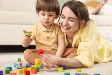 Photo of Mother and son playing with colorful cubes at home