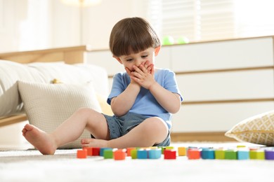 Photo of Cute little child playing with colorful cubes at home
