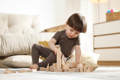 Photo of Cute little child playing with wooden building blocks at home. Space for text