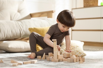 Photo of Cute little child playing with wooden building blocks at home. Space for text