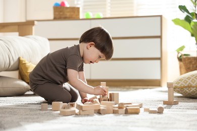 Photo of Cute little child playing with wooden building blocks at home. Space for text