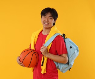 Photo of Student with basketball and backpack on orange background