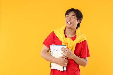 Photo of Student with different notebooks on orange background, space for text