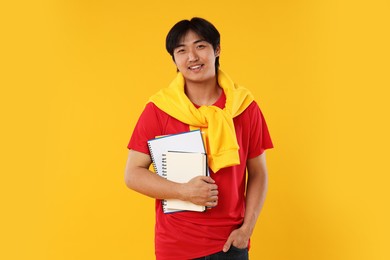 Photo of Student with different notebooks on orange background