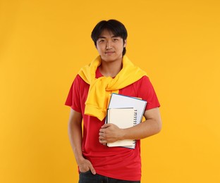 Photo of Student with different notebooks on orange background