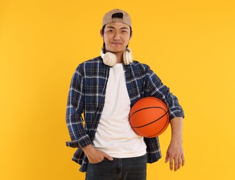 Photo of Student with headphones and basketball ball on orange background