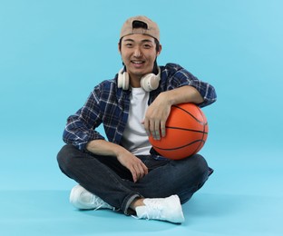 Photo of Student with headphones and basketball ball on light blue background