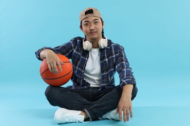 Photo of Student with headphones and basketball ball on light blue background