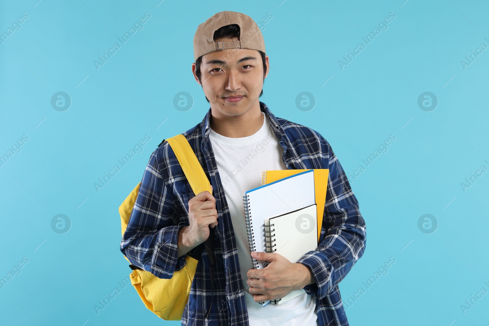 Student with backpack and notebooks on light blue background Photo of Student with backpack and notebooks on light blue background