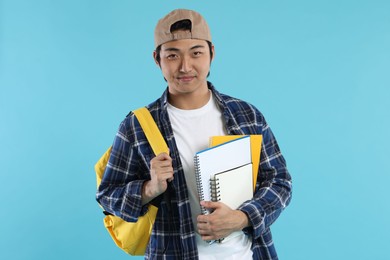 Photo of Student with backpack and notebooks on light blue background