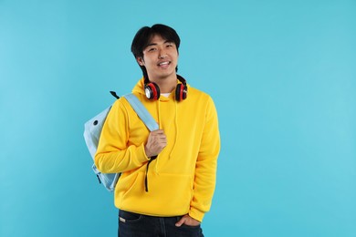 Photo of Student with headphones and backpack on light blue background