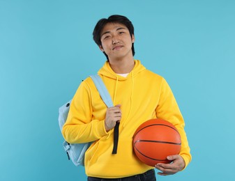 Photo of Student with basketball ball and backpack on light blue background