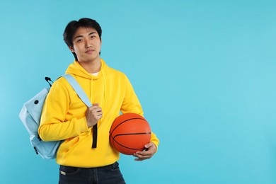 Photo of Student with basketball ball and backpack on light blue background, space for text