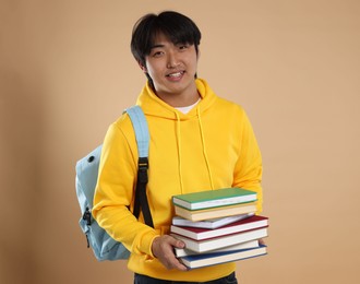 Photo of Student with books and backpack on beige background