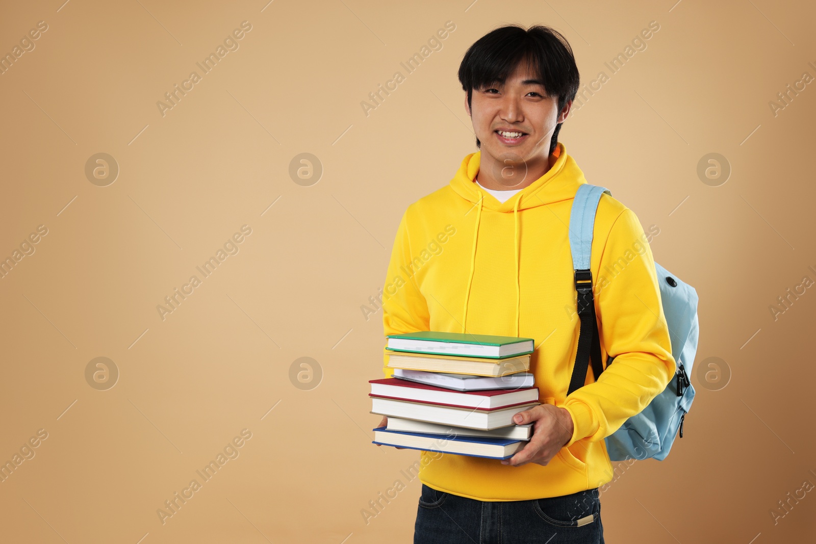 Student with books and backpack on beige background, space for text Photo of Student with books and backpack on beige background, space for text
