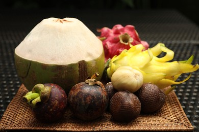 Photo of Different tropical fruits on wicker table, closeup