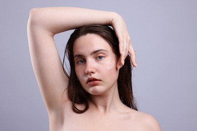 Photo of Portrait of woman with skincare product on her face against grey background, closeup
