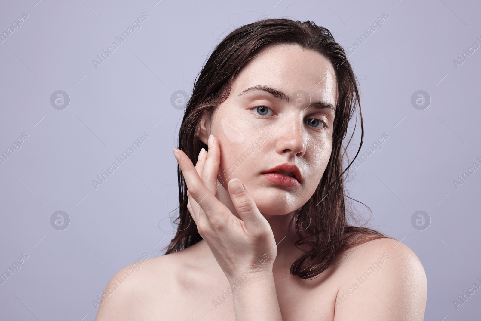 Portrait of woman with skincare product on her face against grey background, closeup Photo of Portrait of woman with skincare product on her face against grey background, closeup