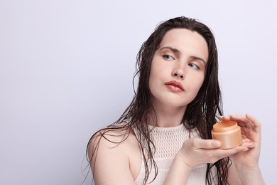 Photo of Beautiful woman with jar of skincare product on light grey background, closeup. Space for text