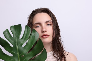 Photo of Portrait of beautiful woman with natural skin complexion and monstera leaf on grey background, closeup