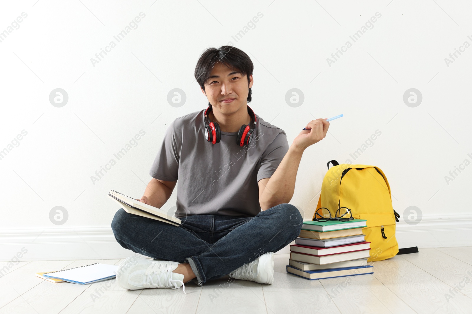 Student with notebook and pen studying on floor indoors Photo of Student with notebook and pen studying on floor indoors