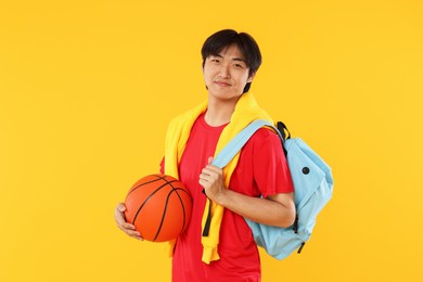 Photo of Student with basketball and backpack on orange background