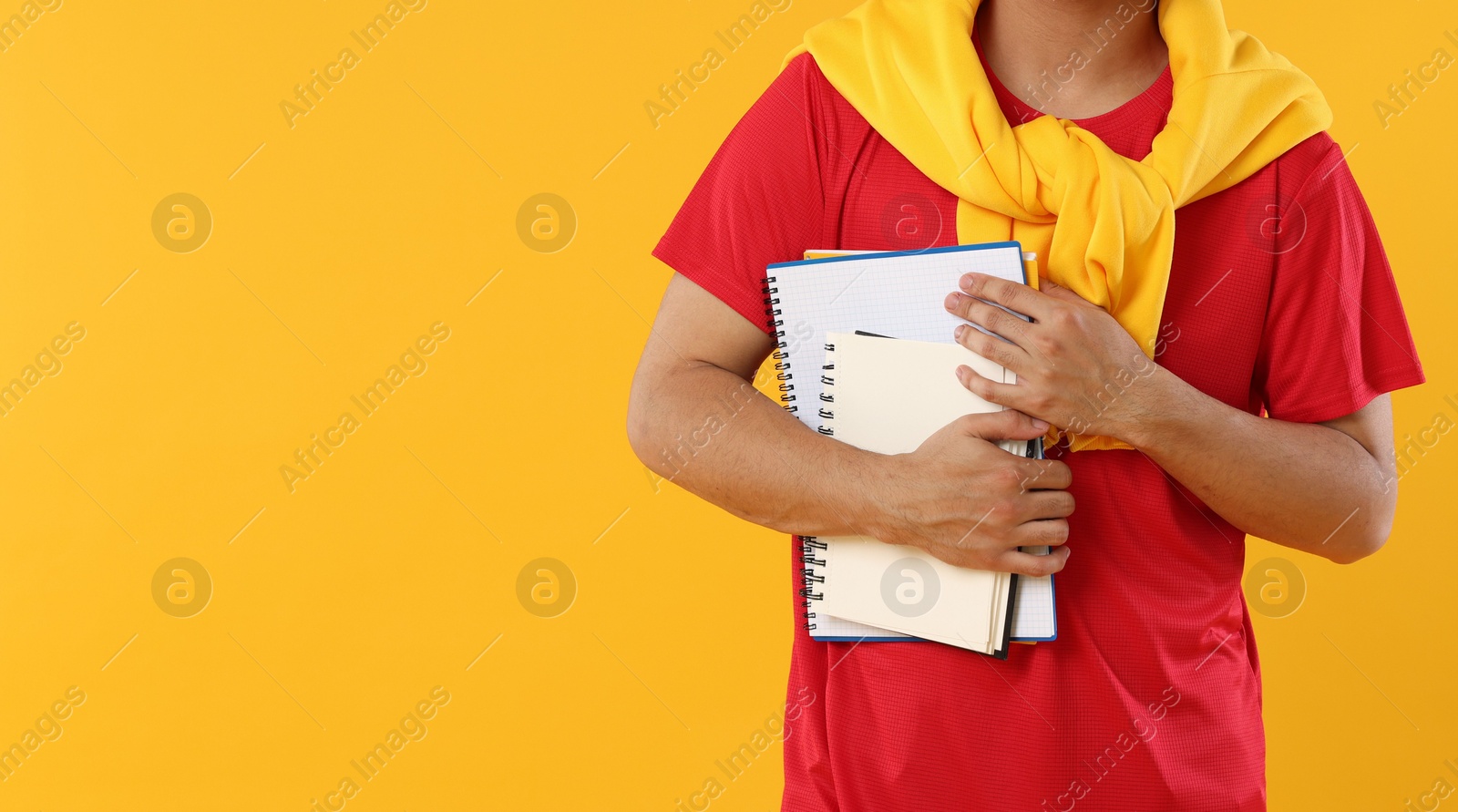 Student with different notebooks on orange background, closeup. Space for text Photo of Student with different notebooks on orange background, closeup. Space for text
