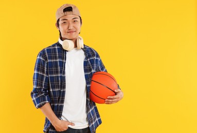 Photo of Student with headphones and basketball ball on orange background, space for text