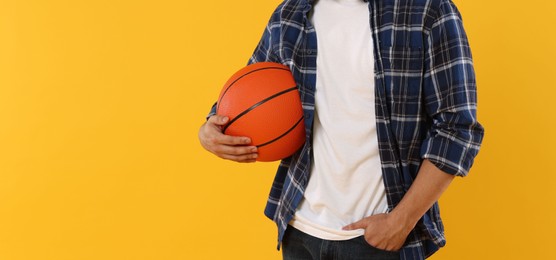 Photo of Student with basketball ball on orange background, closeup. Space for text