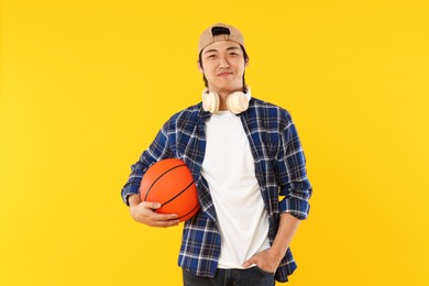 Photo of Student with headphones and basketball ball on orange background