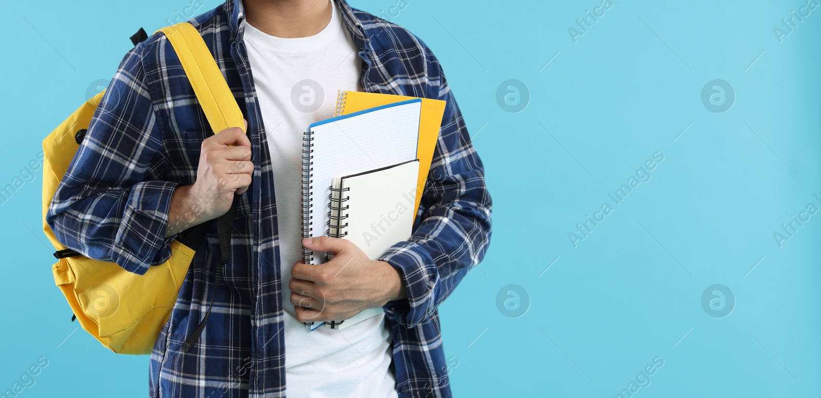 Student with backpack and notebooks on light blue background, closeup. Space for text Photo of Student with backpack and notebooks on light blue background, closeup. Space for text